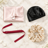 Coffret Nuit des cheveux : taie rose clair, bonnet noir, ruban bordeaux et chouchou champagne en satin